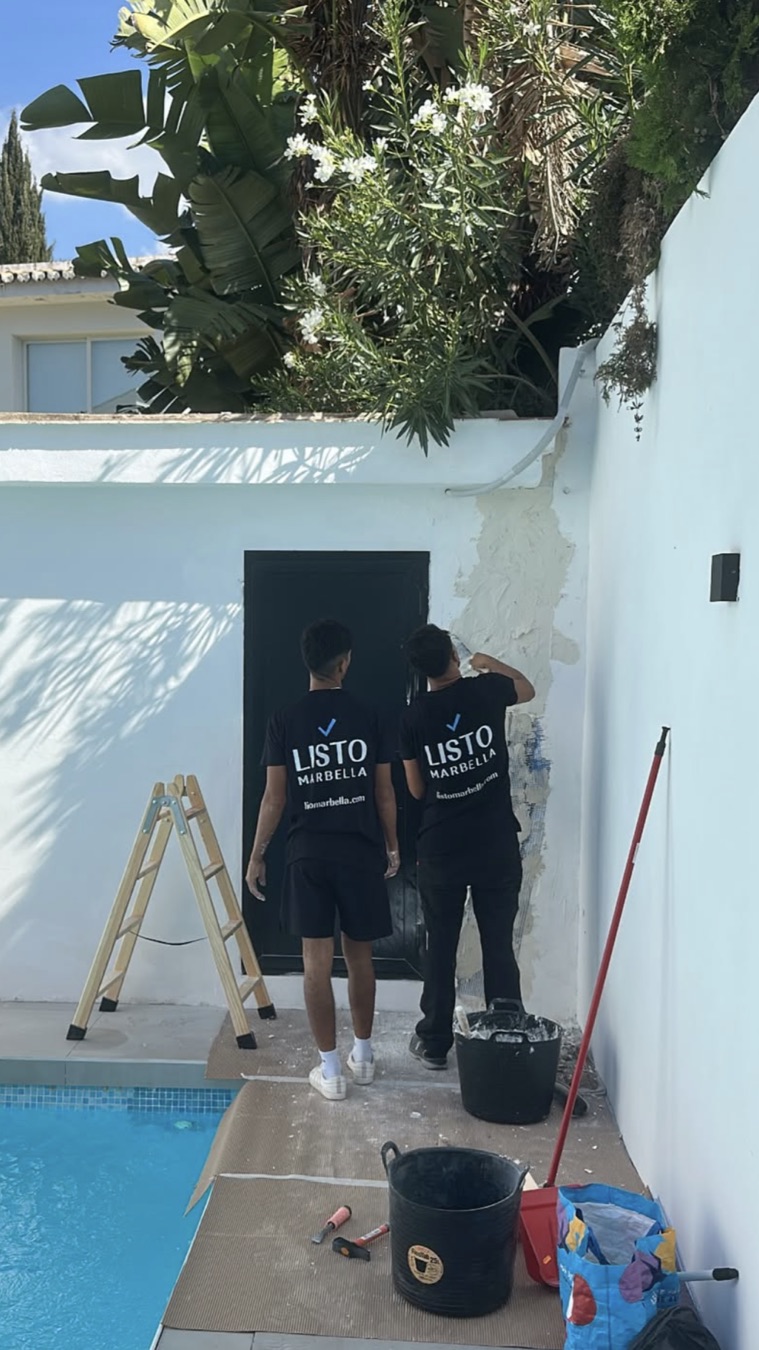 Dos profesionales de Listo reparando la pared junto a la piscina